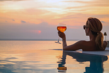 woman watching the sunset with a cocktail in an infinity pool, showcasing luxury lifestyle, vacation
