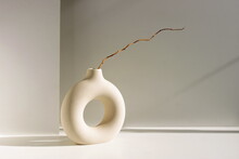 Modern Beige Ceramic Vase  With Branch And Sunlight Shadow On White Table Near Gray Wall.Copy Space, Minimal Scandinavian Interior Accessories. 