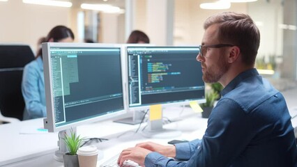 hardworking caucasian programmer sitting in front of multiple displays. young man writing code for c