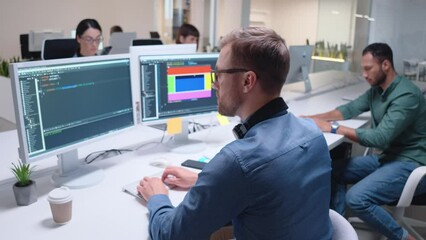 Hardworking mixed-raced developers working on computers together at modern office. Busy people creating and developing software for users. On screen visible diagrams and programing codes.
