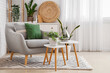 Leinwandbild Motiv Cozy grey armchair with cushions and houseplants on tables in interior of light living room