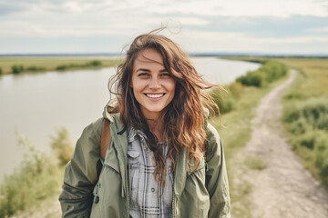 young adult woman traveling, hiking along a small river in nature, fictional place