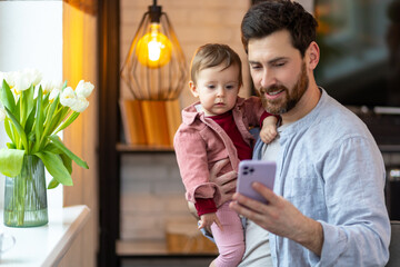 Dad and toddler child looking at cellphone, father holding phone taking selfie with little girl kid