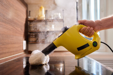 Cleaning kitchen hob with a steam cleaner.