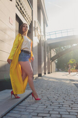 Displaying fashion tendencies. Dark-haired attractive woman posturing in bright yellow fluffy cloak.