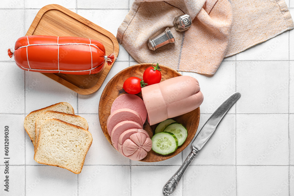 Tasty boiled sausages with vegetables and bread on white tile background