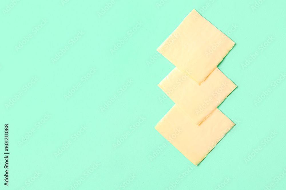 Slices of tasty processed cheese on turquoise background