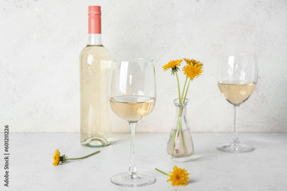 Bottle and glasses of dandelion wine on white table