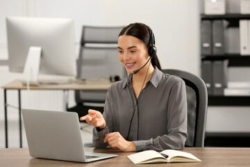 Wall Mural - Hotline operator with headset working on laptop in office