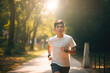 © MVProductions - Young asian man running in park or forest, summer season. Generative AI