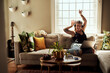 © Chanelle Malambo/peopleimages.com - Music, headphones and woman on sofa and laptop dancing, happy energy and mental health in boho apartment. Young person listening to audio technology, electronics and computer in living room or home