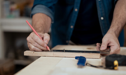 Craftsman working at tabletop with pencil marking on wood plank in renovation at home. Carpenter working with equipment on wooden table in carpentry shop. Joiner woodworking furniture making industry