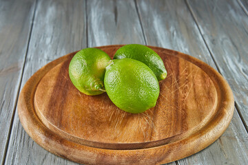 Poster - Limes on wooden stand on gray wooden background