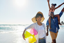 Black Family, Beach Ball And Summer At The Beach While Happy And Walking Together Holding Hands. Man, Woman And A Girl Child Excited About Holiday At The Ocean With Freedom, Happiness And Fun Outdoor