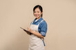 © PBXStudio - Cheerful asian woman in apron with a tablet in hand isolated on background in studio. Small business startup concept.