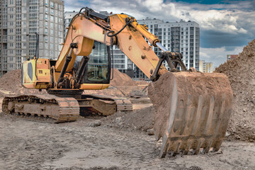 Wall Mural - Crawler Excavator Machine Unloading Sand or Soil at Construction Area Background. Close-up of an excavator bucket with an extended boom. Rental of construction equipment. earthworks contractor.