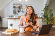 © Art_Photo - Young smiling asian woman happy relax use laptop conference work,learning education, shopping, study online, webinar, podcast,creative girl holding smartphone positive, success, excited at home