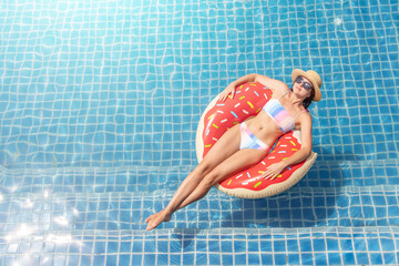 Wall Mural - Beautiful woman with inflatable donut in pool