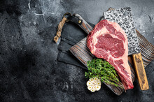 Dry Aged Tomahawk Rib Eye Steak, Raw Beef Meat On Butcher Table. Black Background. Top View. Copy Space