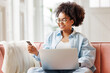 © JenkoAtaman - beautiful young smiling ethnic curly  woman  doing online shopping while sitting on sofa .