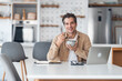 © Jelena - Portrait of a smiling male freelancer eating cereal with milk and working on a laptop.