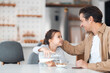 © Jelena - A smiling daughter and father looking at each other during breakfast time.