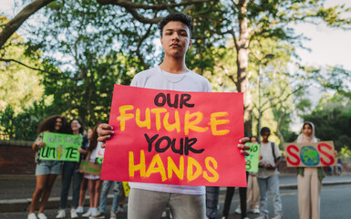 Wall Mural - Teenage boy holding a banner sign during a climate change demonstration