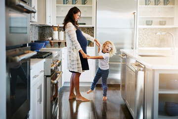 Happy family, pregnant woman with boy child and in kitchen at their home with lens flare. Mother with love or care, mother and cheerful parent with son bonding with dance in their house together