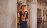 Fototapeta Uliczki - tourist trip to old Dubai, UAE. Asian Woman tourist holding UAE flag in old narrow streets of Bur Dubai and Creek, Al Seef Heritage Souq. Travel and sightseeing journey concept