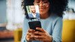 © Gorodenkoff - Augmented Reality Dating Concept: Awesome Black Girl Uses Smartphone for Browsing Social Media Dating App. Lovely Young Brazilian Woman Searching for True Love with the Help of AI Powered Software