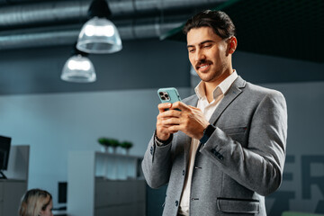 Poster - Handsome young arab man in formal wear using smartphone in office