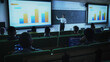 © Gorodenkoff - Young University Professor Explaining the Importance of Branding and Marketing Campaigns to a Group of Diverse Multiethnic Students in a Dark Auditorium. Female Teacher Showing Business Charts Data