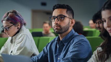 Fototapete - Young Handsome Male Student Studying in University with Diverse Multiethnic Classmates. Young Man is Writing Down Lecture Summary in Notebook to Prepare for College Exams