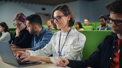 Aufkleber - Young Female Student Studying in University with Diverse Multiethnic Classmates. She is Focused and Using a Laptop Computer. Patiently Listening to Professor's Lecture and Taking Notes