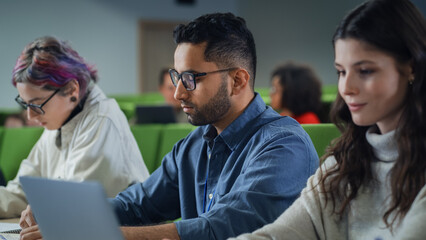 Poster - Young Handsome Male Student Studying in University with Diverse Multiethnic Classmates. Young Man is Writing Down Lecture Summary in Notebook to Prepare for College Exams