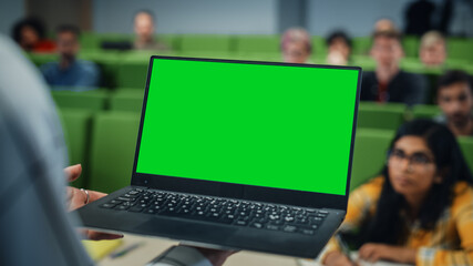 Fototapete - Close Up of an University Professor Using a Laptop Computer with a Green Screen Mock Up Display. Female Teacher Giving a Lecture to a Class of Talented Diverse Young Men and Women.