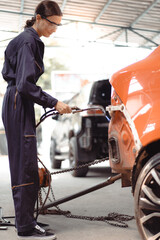 Wall Mural - Woman welder welding damaged body car with blue spark at workshop. Female auto mechanic working at repair garage fixing broken vehicle with skill. Women worker in automotive maintenance industry.