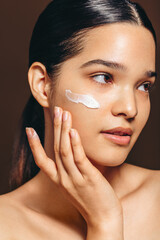 Face scrub with an exfoliating cream; woman cleansing her face with a beauty product