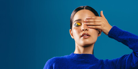 Wall Mural - Young woman covers her eye, highlighting her striking graphic eyeliner