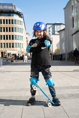 Wall Mural - portrait of happy schoolboy in purple helmet, holding blue urban cruiser, skateboard