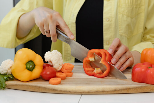 Wall Mural - female hands cut vegetables with a knife on a wooden cutting board, healthy eating concept