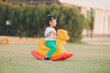 happy and fun of asian baby cute girl play on toy horse equipment in playground on beautiful light of evening time