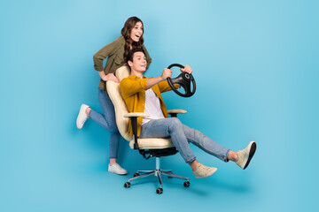 Poster - Full length photo of funny couple brother sister play push chair hold steering wheel fast speed driving excited isolated on blue color background