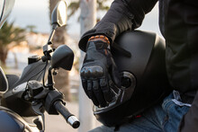 Close Up Of A Gloved Biker's Hand Resting On His Helmet. Road Safety Concept.