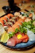 Mixed Sushi Set nigiri, rolls and sashimi served in traditional Japan black Sushioke round plate.