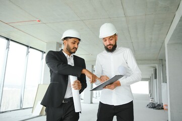 Wall Mural - Multiethnic business team. Construction concept. Indian and Arab engineers inspect the construction.