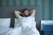© Евгений Шемякин - Young happy bearded handsome sleepy man lay in bed in bedroom at home in early morning, smile and looking at camera