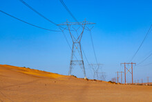 Electric Pylon In The Desert With Wooden Pile
