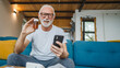 © Miljan Živković - senior man sit at home hold bottle medicine pills drugs and smartphone