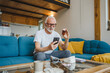 © Miljan Živković - senior man sit at home hold bottle medicine pills drugs and smartphone